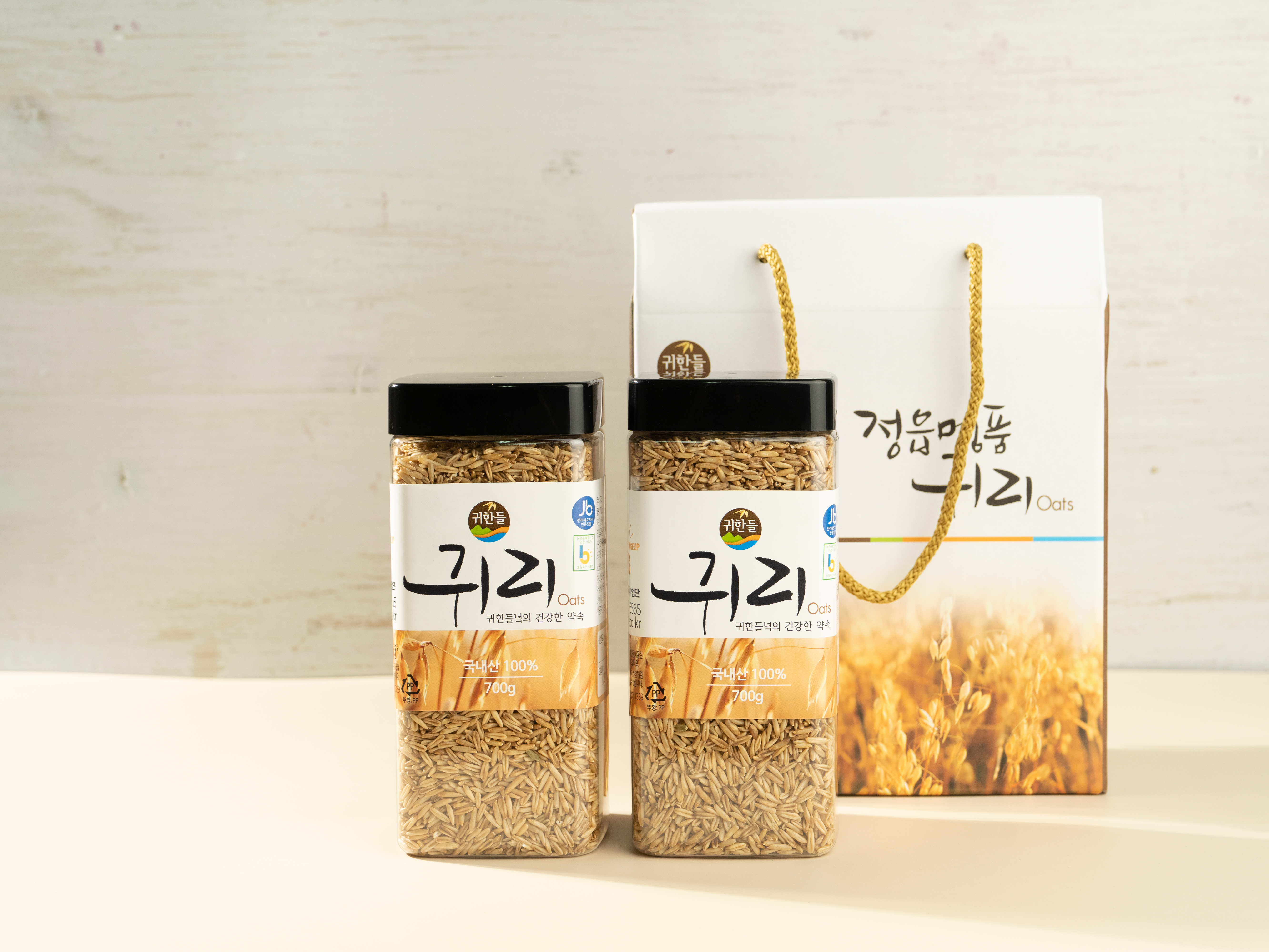 손잡이가 달린 정읍명품귀리 전용 선물박스와 나란히 놓인 국산 귀리 700g 병 2개