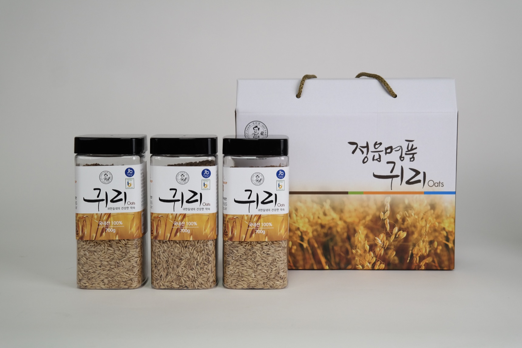 손잡이가 달린 정읍명품귀리 전용 선물박스와 나란히 놓인 국산 귀리 700g 병 3개
